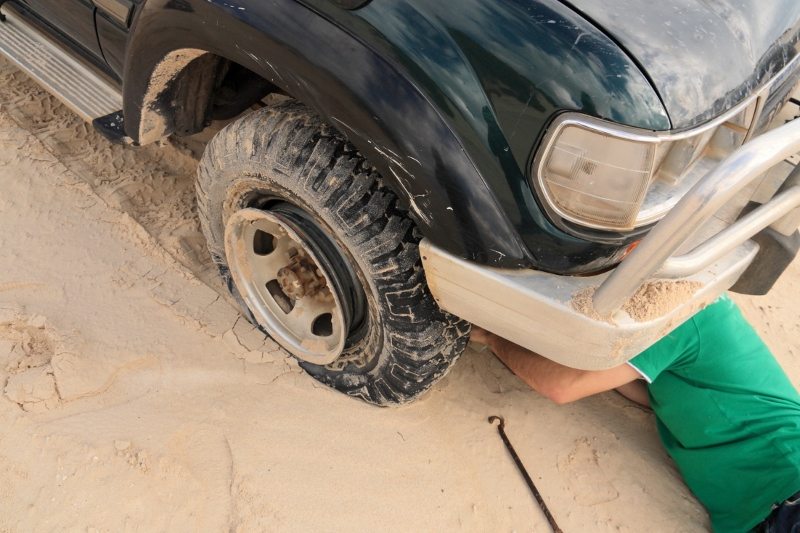 Technician changing a flat tire on a car