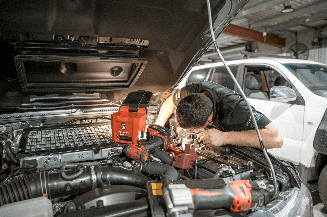 Mechanic diagnosing a car problem under the hood in a repair shop