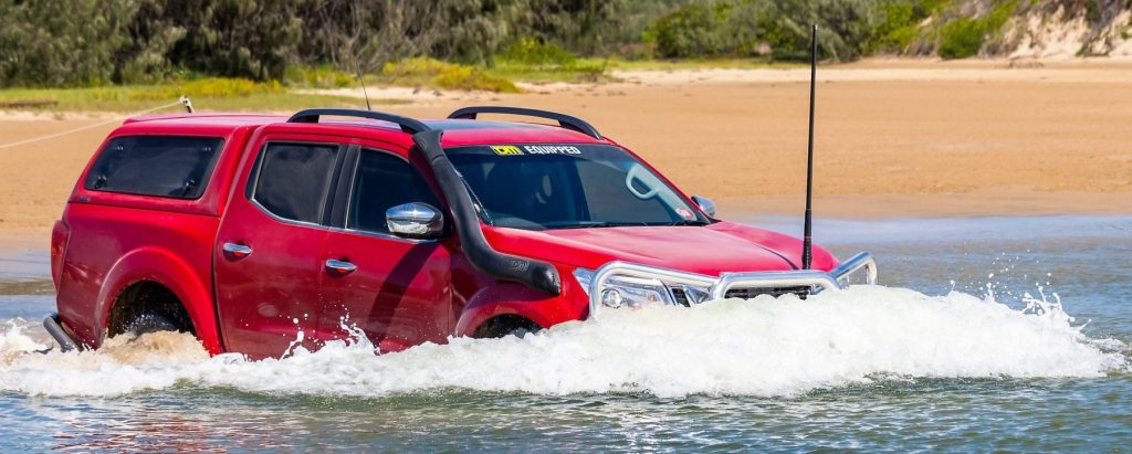 Large vehicle crossing body of water in natural setting