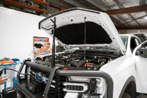 Mechanic working on a car with the hood open in a repair shop