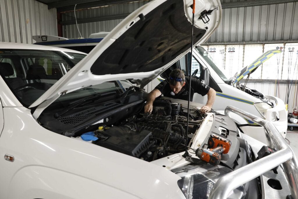 Close-up view of a mechanic using tools to diagnose a car engine issue in a garage