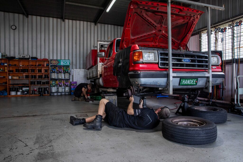 Mechanics working on different parts of multiple cars in a garage