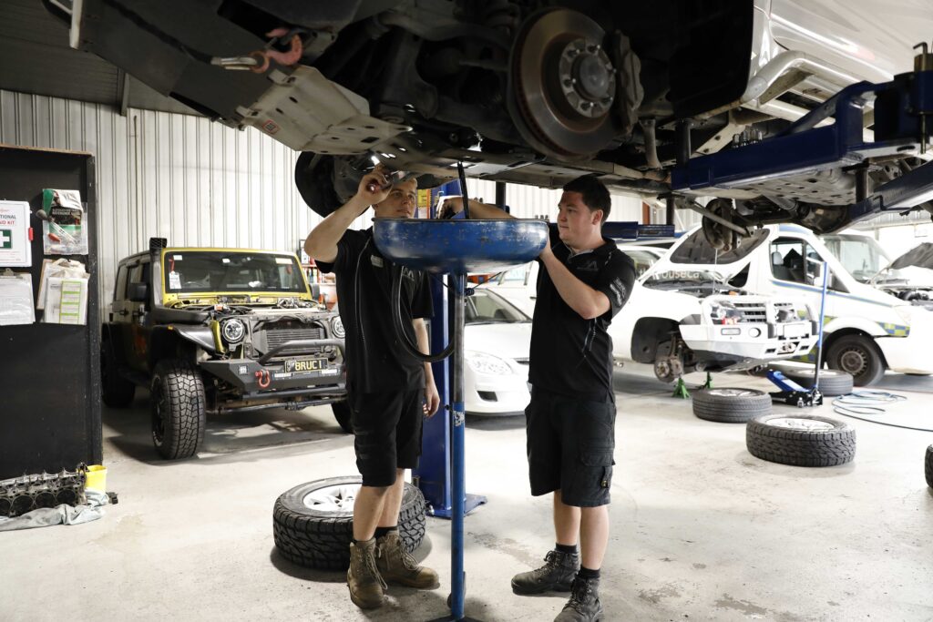Car mechanics in a workshop performing an oil change on a vehicle