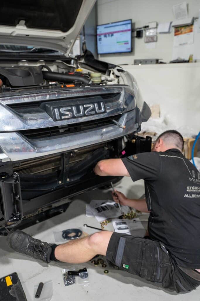 Mechanics inspecting a car engine inside a garage, focused on resolving a mechanical problem