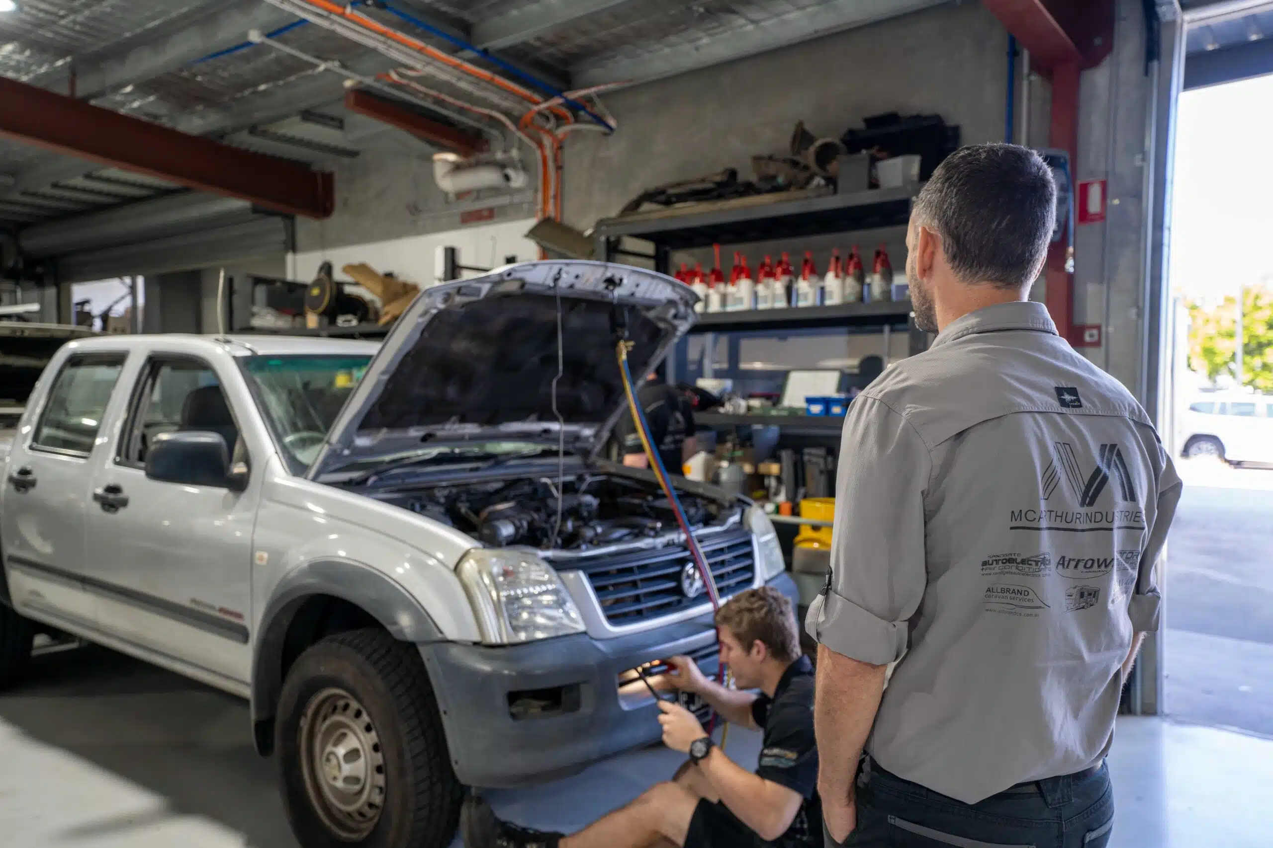 Car mechanic troubleshooting a car issue beneath a lifted vehicle in a professional repair shop.