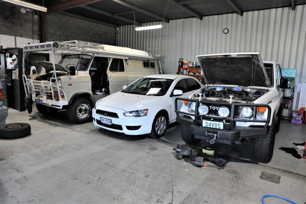 Mechanic troubleshooting a car issue under the hood in a garage.