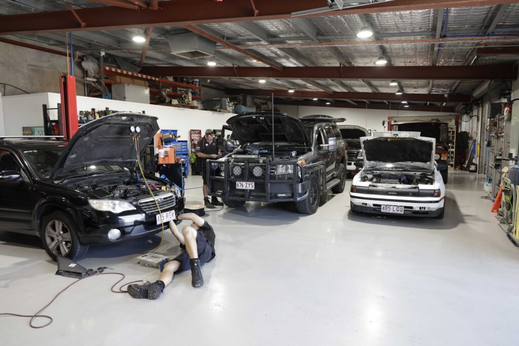 Busy car mechanic working on multiple vehicles in a workshop