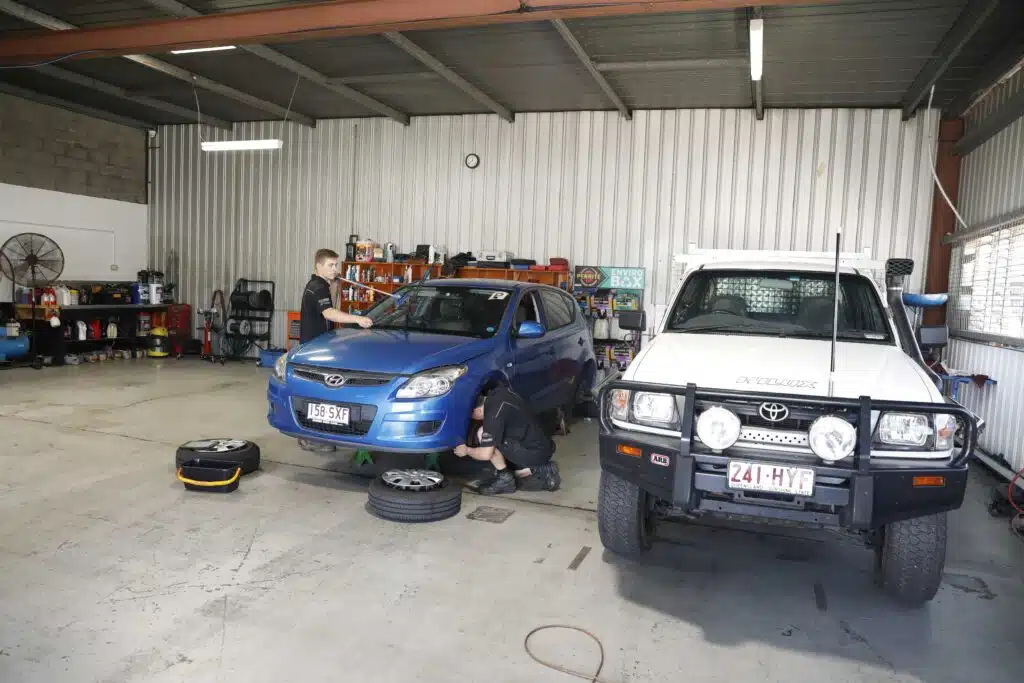 Car undergoing inspection in a workshop setting.
